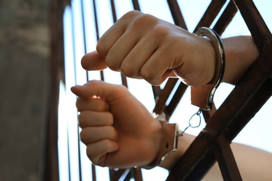 Man handcuffed in jail outdoors, low angle view. Criminal law