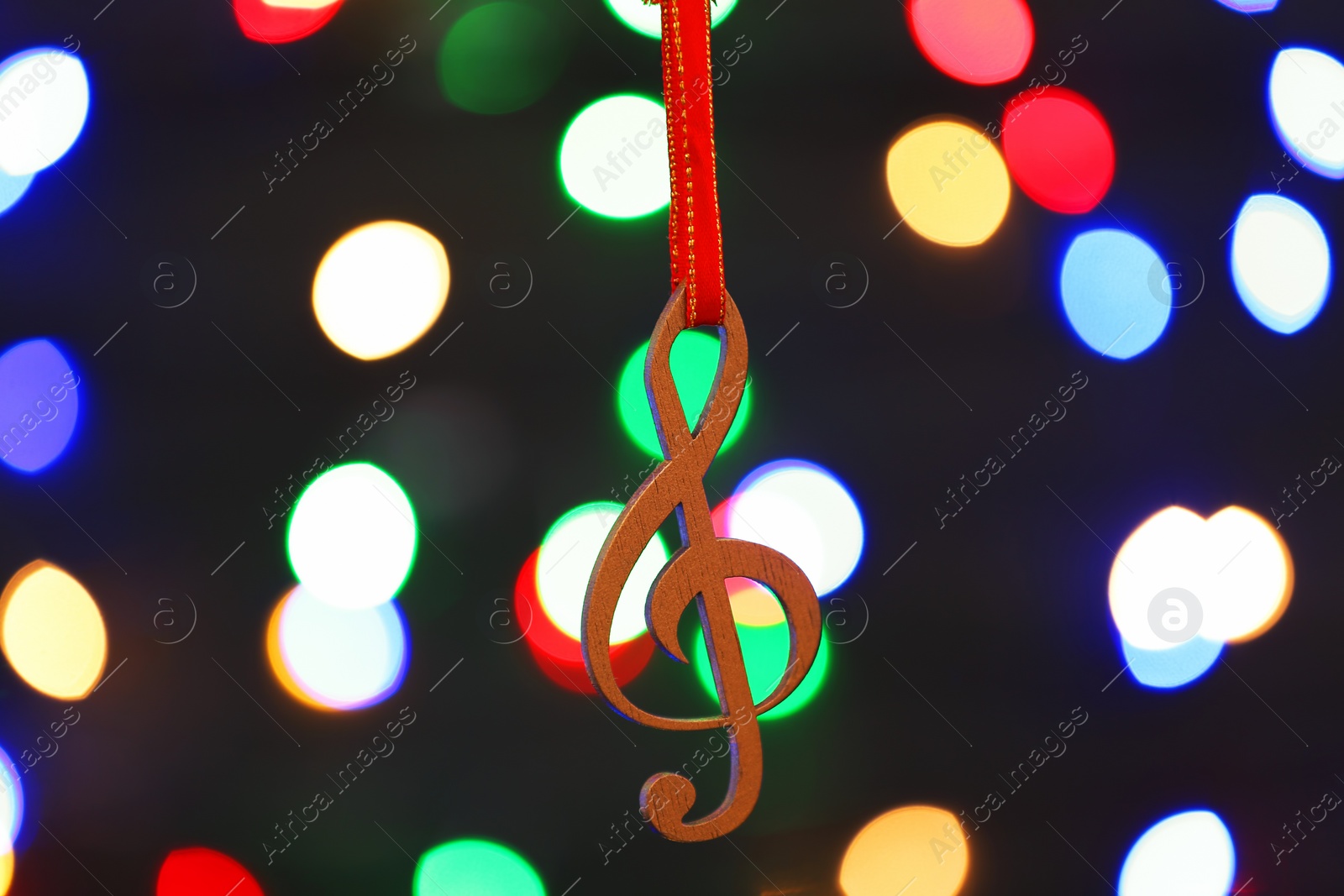 Photo of Wooden treble clef against blurred lights. Christmas music