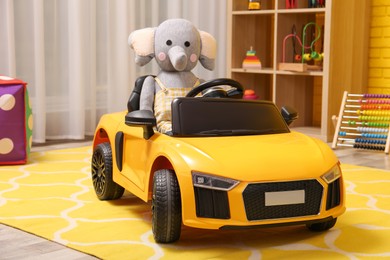 Child's electric car with toy elephant in playroom