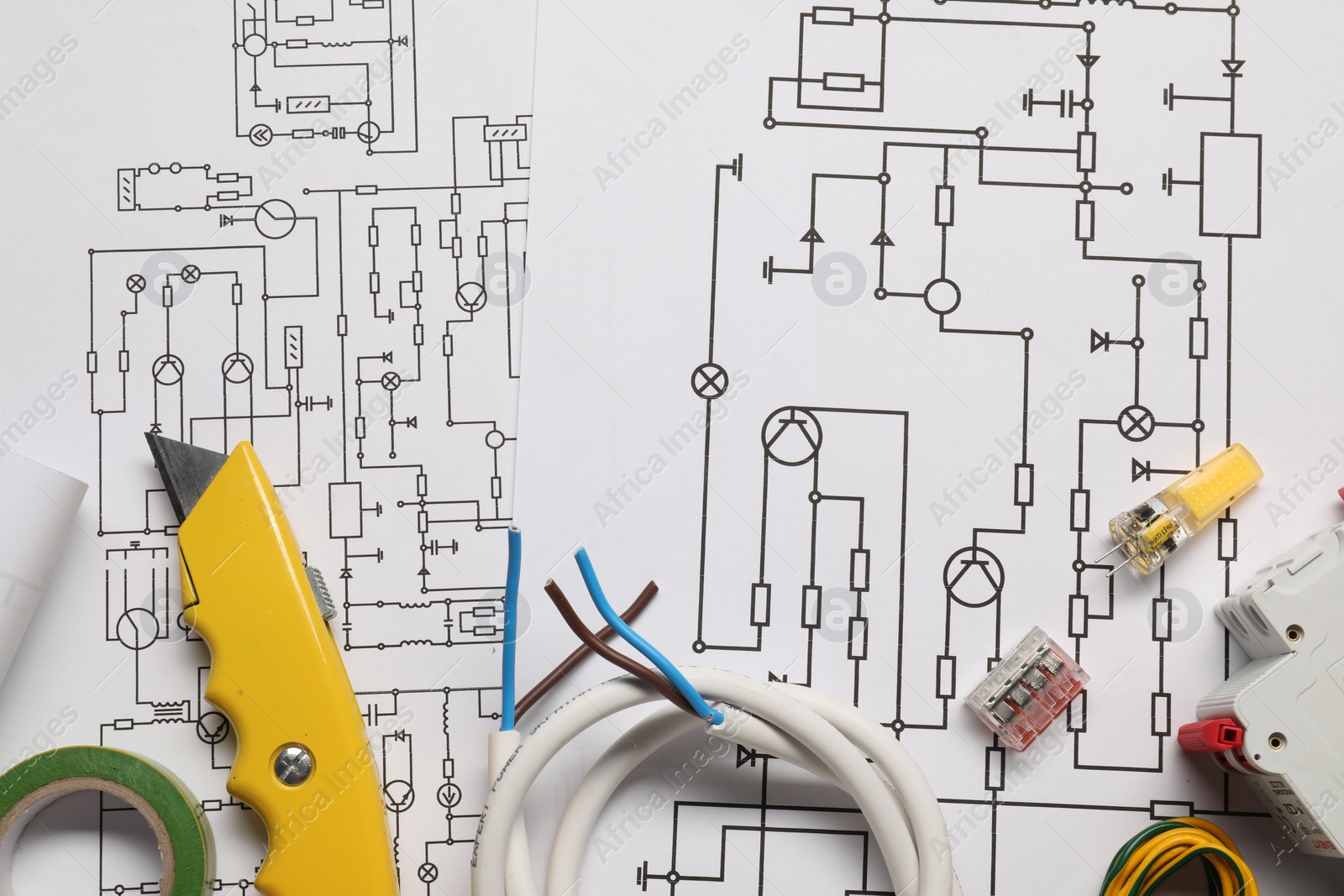 Photo of Wires, knife and other electrician's equipment on wiring diagrams, flat lay