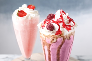 Tasty milk shakes with toppings on color background, closeup