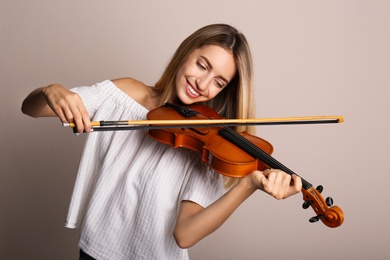 Photo of Beautiful woman playing violin on beige background