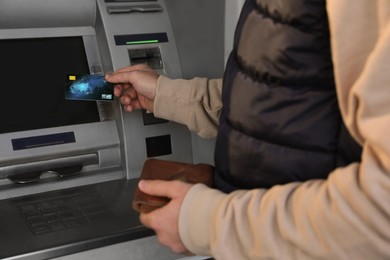 Young man with credit card near cash machine, closeup