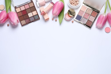 Flat lay composition with eyeshadow palettes and beautiful flowers on white background, space for text