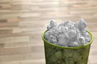 Photo of Metal bin with crumpled paper on floor, space for text