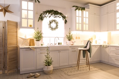 Photo of Small Christmas trees and festive decor in kitchen