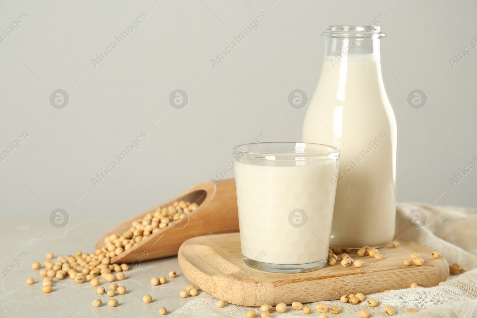 Photo of Fresh soy milk and beans on light grey table, space for text