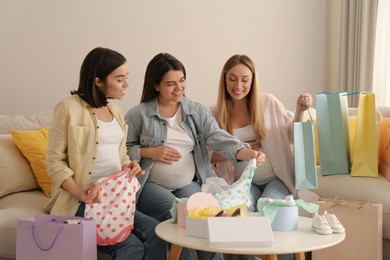 Photo of Happy pregnant women spending time together in living room after shopping