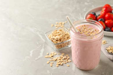 Photo of Jar of tasty berry oatmeal smoothie on grey table, space for text