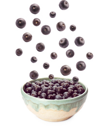 Fresh acai berries falling into bowl on white background
