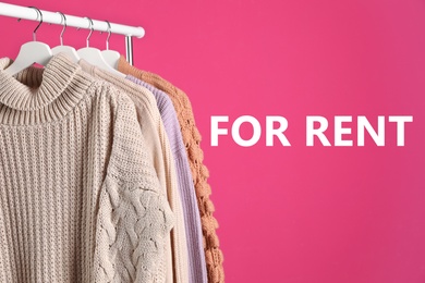 Image of Collection of warm clothes for rent hanging on rack against pink background