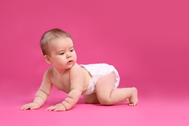 Photo of Cute little baby in diaper crawling on pink background