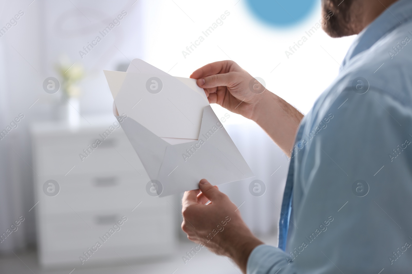 Photo of Man holding envelope with greeting card at home, closeup