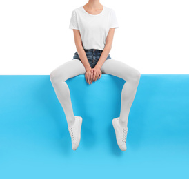 Woman wearing bright tights and stylish shoes sitting on color background, closeup