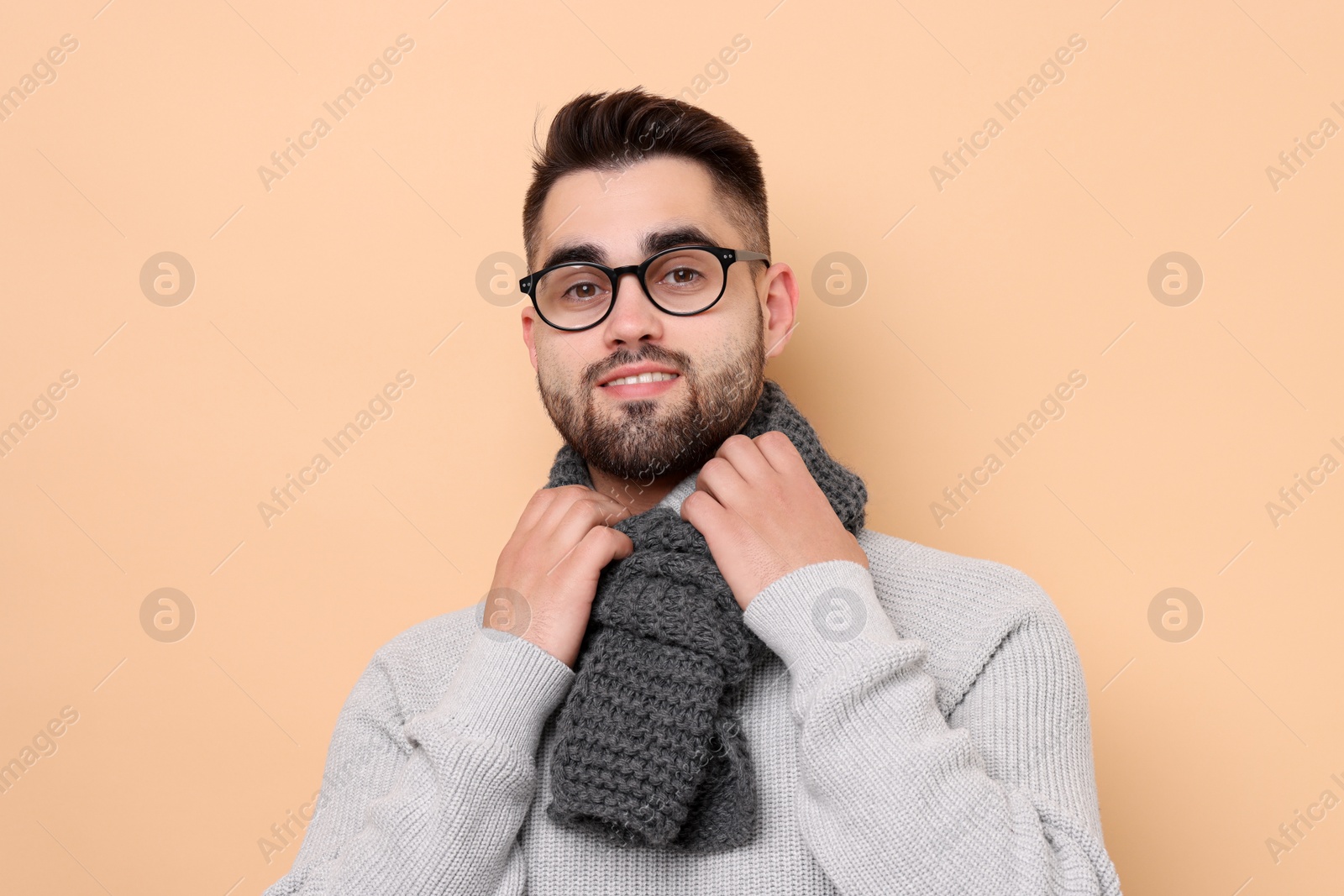 Photo of Smiling man in knitted scarf on beige background