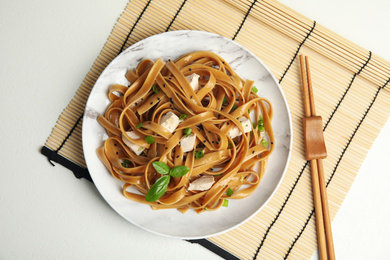 Photo of Tasty buckwheat noodles with meat served on white table, flat lay