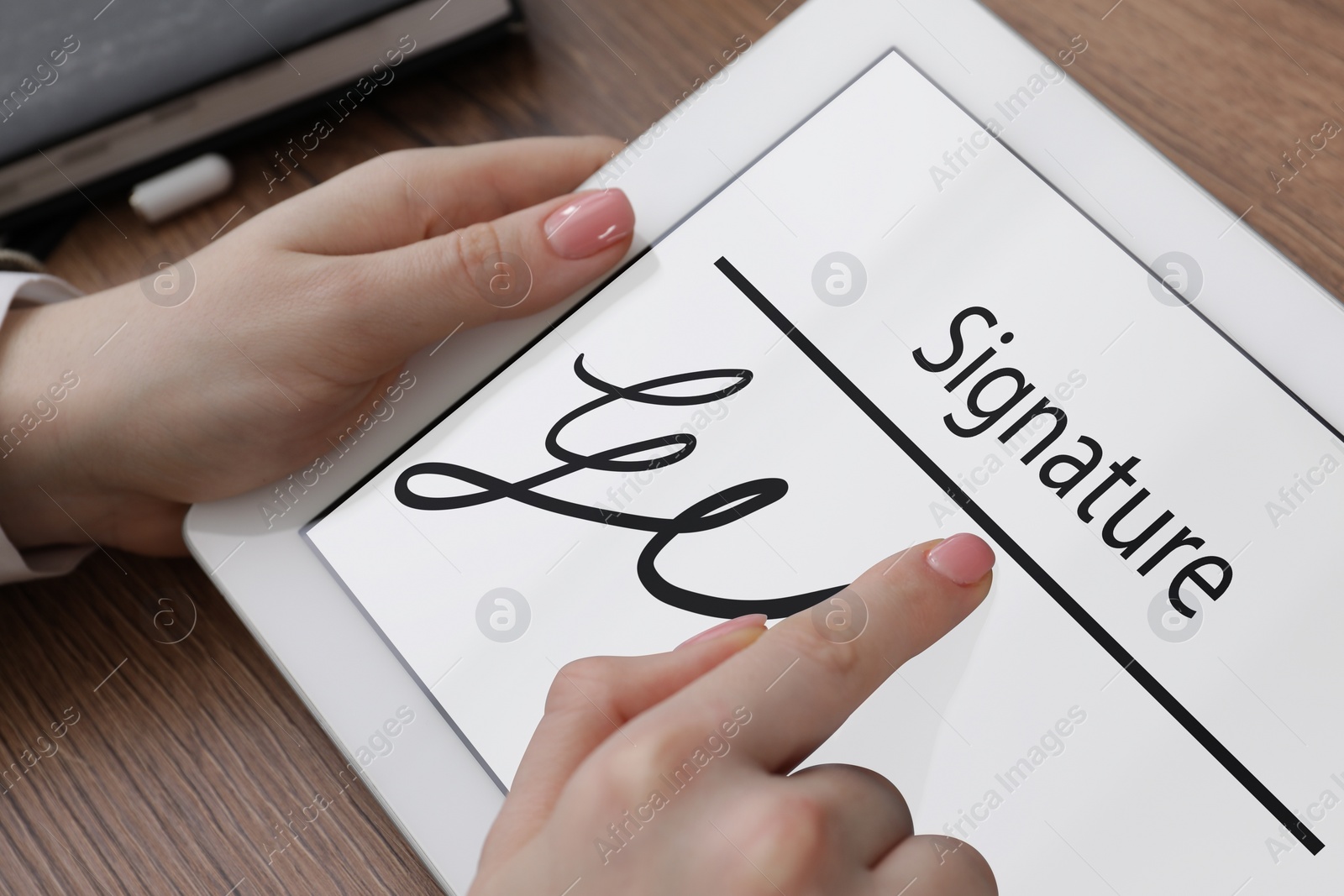Image of Electronic signature. Woman using tablet at wooden table, closeup