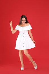 Photo of Young woman wearing stylish white dress on red background