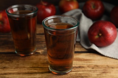 Photo of Delicious cider and ripe red apples on wooden table