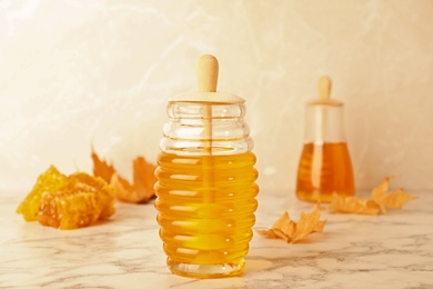 Photo of Jar with tasty honey and dipper on marble table