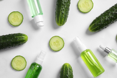 Photo of Flat lay composition with fresh cucumber and cosmetic bottles on white background