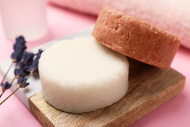 Photo of Solid shampoo bars and lavender on pink table, closeup. Hair care