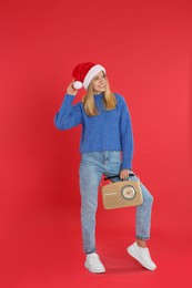 Happy woman with vintage radio on red background. Christmas music