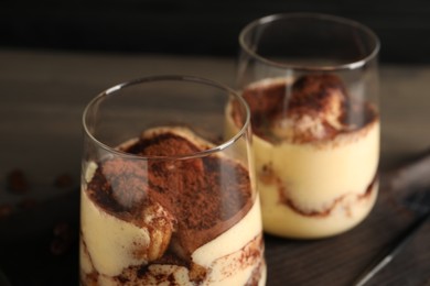 Photo of Delicious tiramisu in glasses on table, closeup