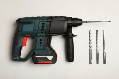 Photo of Modern electric power drill and different bits on white table, flat lay