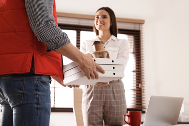 Photo of Courier giving order to young woman in office. Food delivery service