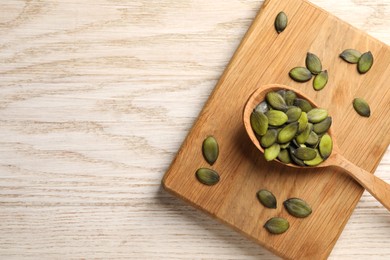 Spoon with pumpkin seeds on wooden table, top view. Space for text