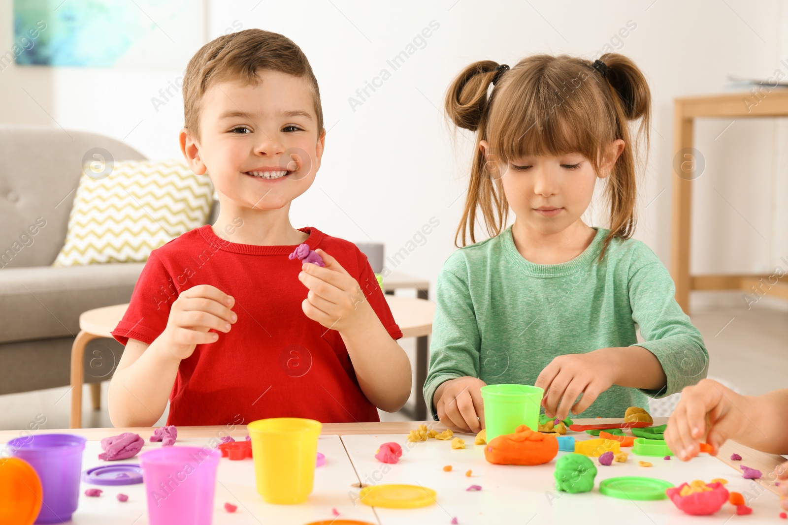 Photo of Cute little children using play dough at table indoors