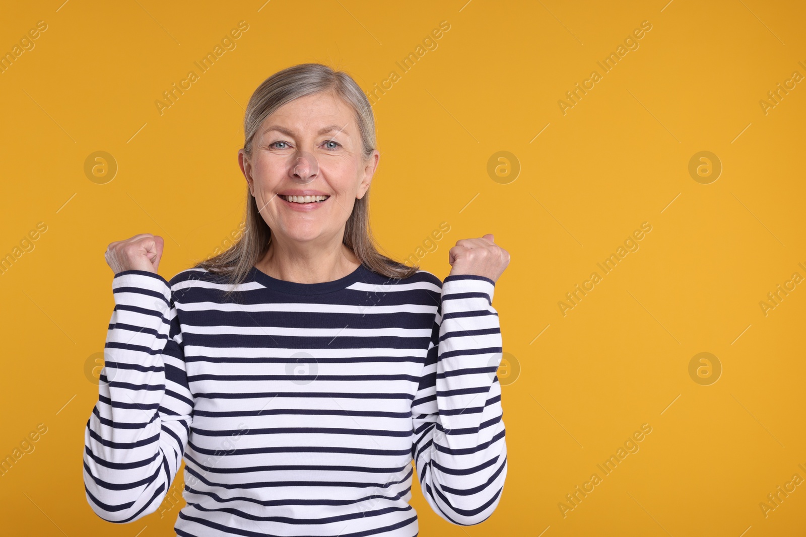 Photo of Portrait of happy surprised senior woman on yellow background, space for text