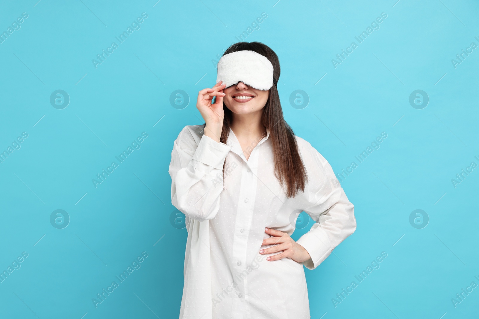 Photo of Woman in pyjama and sleep mask on light blue background