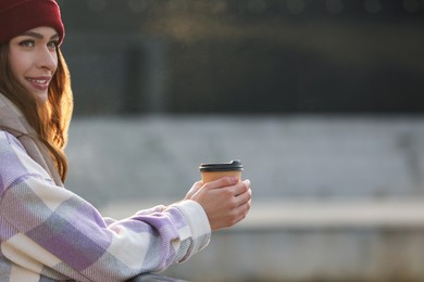 Woman holding paper coffee cup outdoors. Space for text