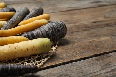 Photo of Many different raw carrots on wooden table, closeup. Space for text