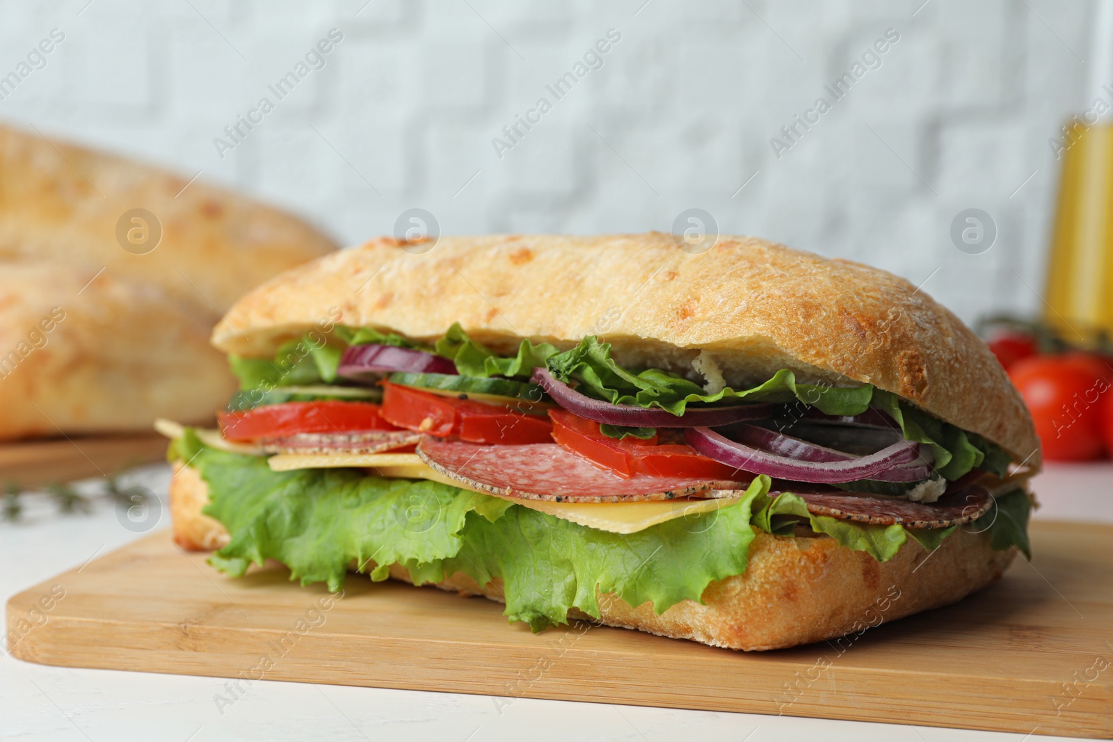 Photo of Delicious sandwich with fresh vegetables and salami on white table