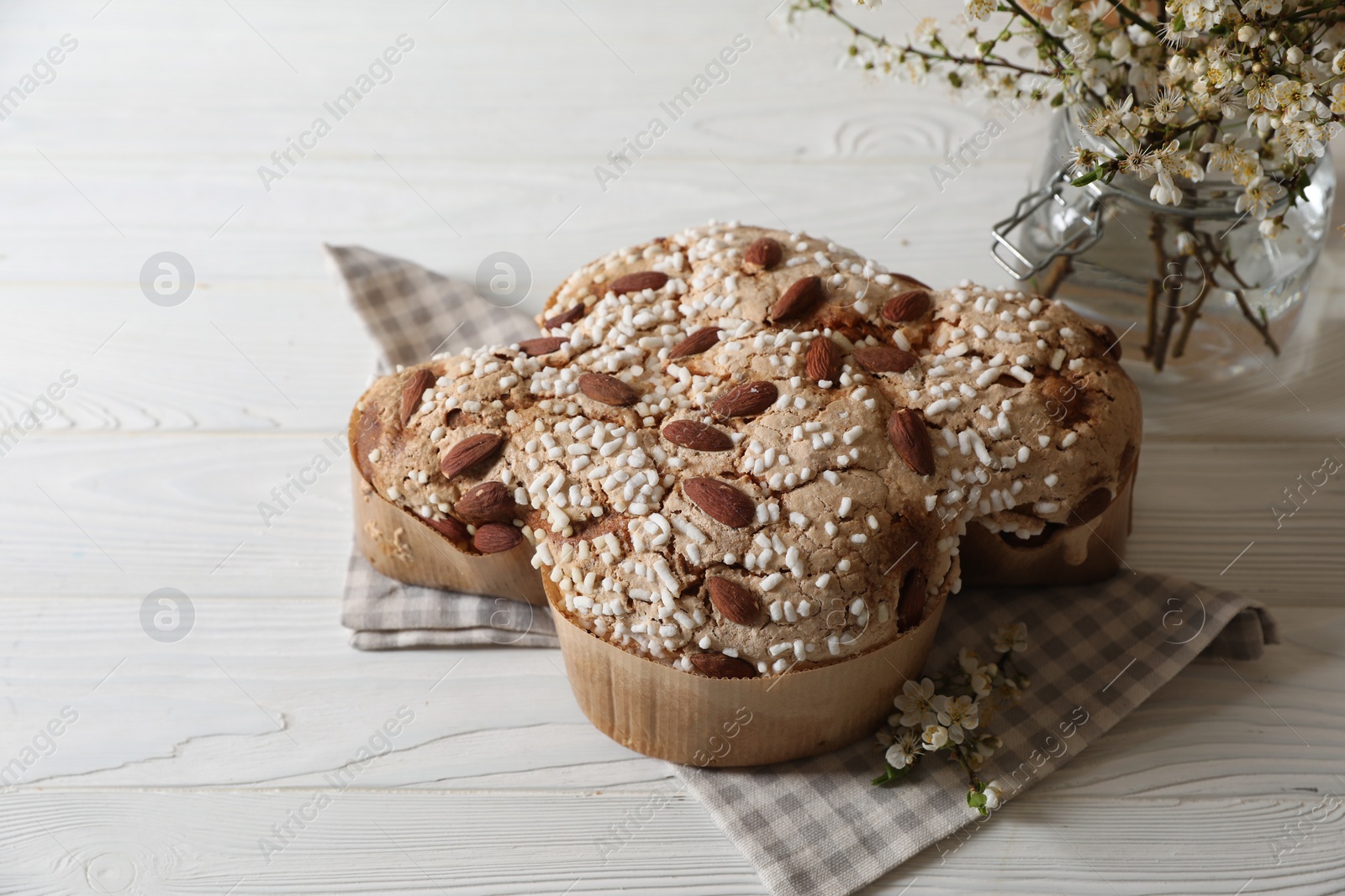 Photo of Delicious Italian Easter dove cake (Colomba di Pasqua) and flowers on white wooden table