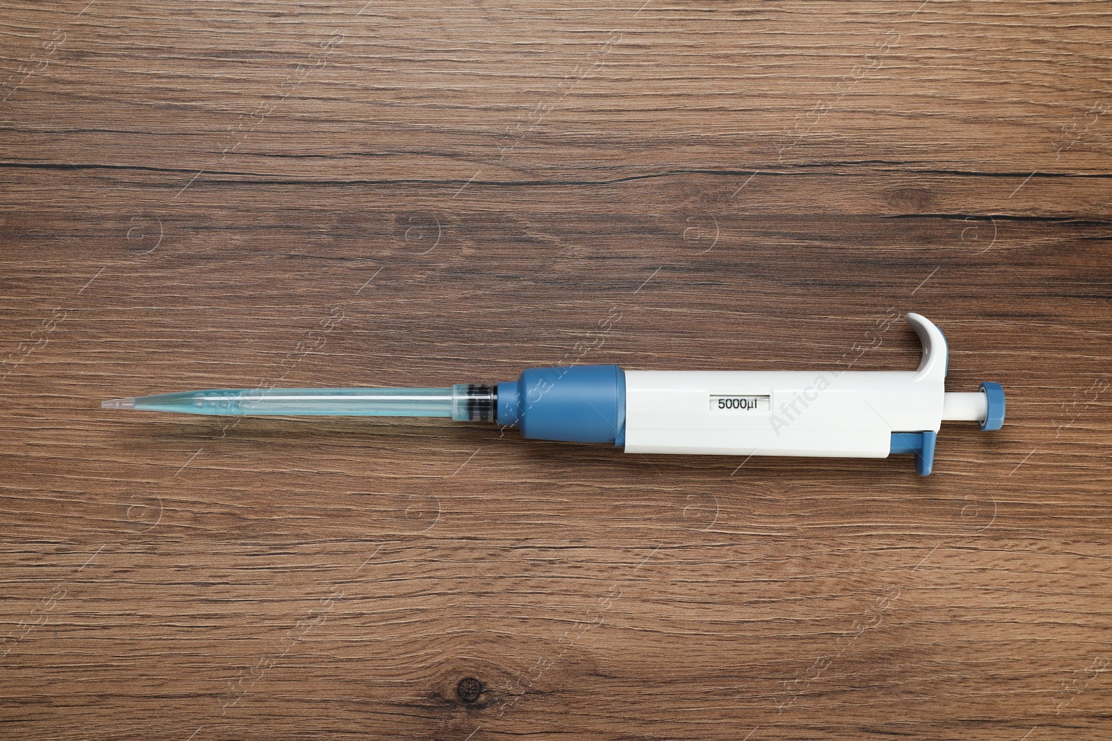 Photo of Laboratory analysis. Micropipette with liquid on wooden table, top view