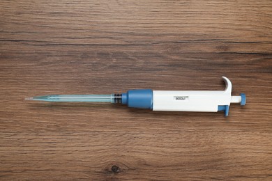 Laboratory analysis. Micropipette with liquid on wooden table, top view