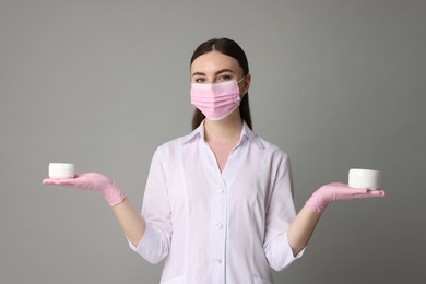 Photo of Cosmetologist with cosmetic products on grey background