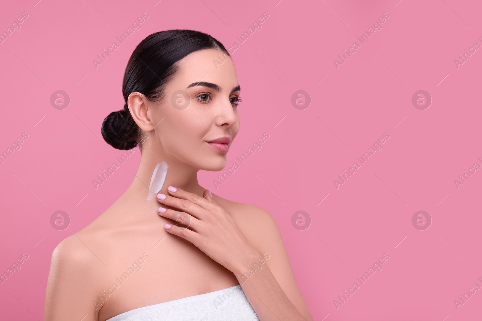 Photo of Beautiful woman with smear of body cream on her neck against pink background, space for text