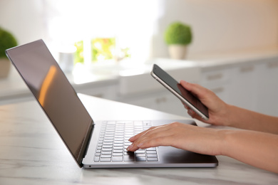 Photo of Woman working with modern laptop at marble table, closeup