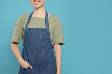 Photo of Woman in clean denim apron on light blue background