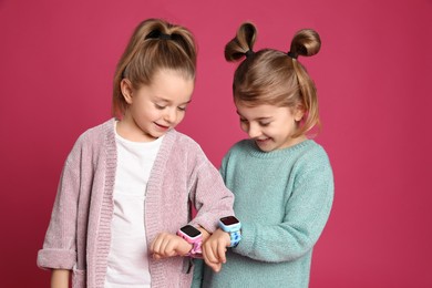 Photo of Little girls with smart watches on pink background