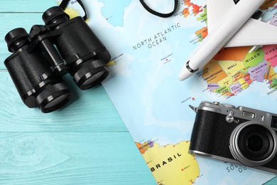 Photo of Flat lay composition with world map and different travel accessories on turquoise wooden table. Planning summer vacation trip