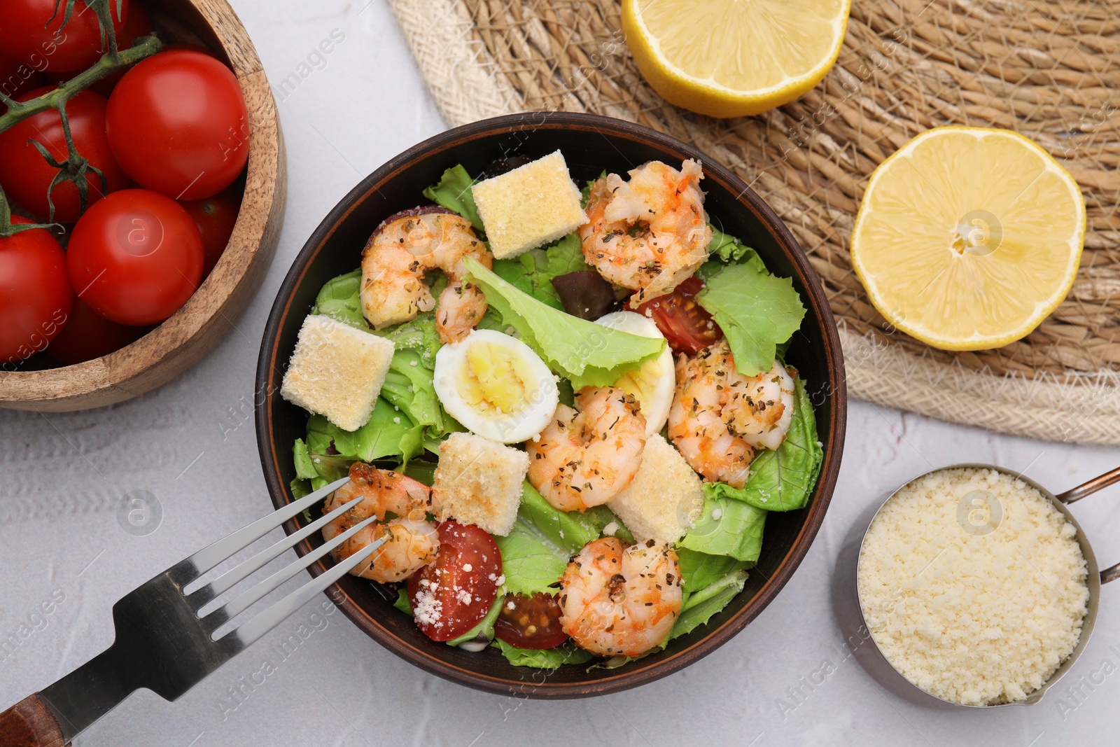 Photo of Delicious Caesar salad with shrimps and fork served on white textured table, flat lay