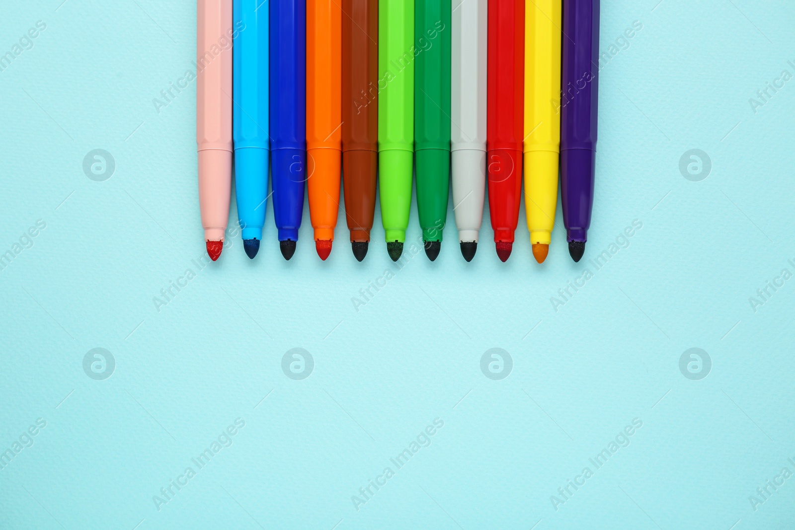 Photo of Different colorful markers on light blue background, flat lay. Space for text