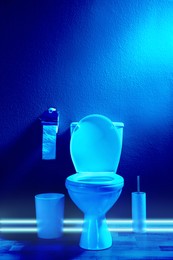 Toilet bowl in public restroom lit with UV blue light