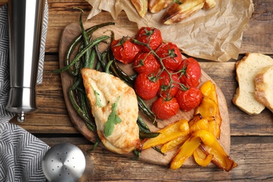 Delicious cooked chicken and vegetables on wooden table, flat lay. Healthy meals from air fryer